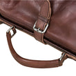 Load image into Gallery viewer, Brown leather bag with metal hardware on a light wooden surface