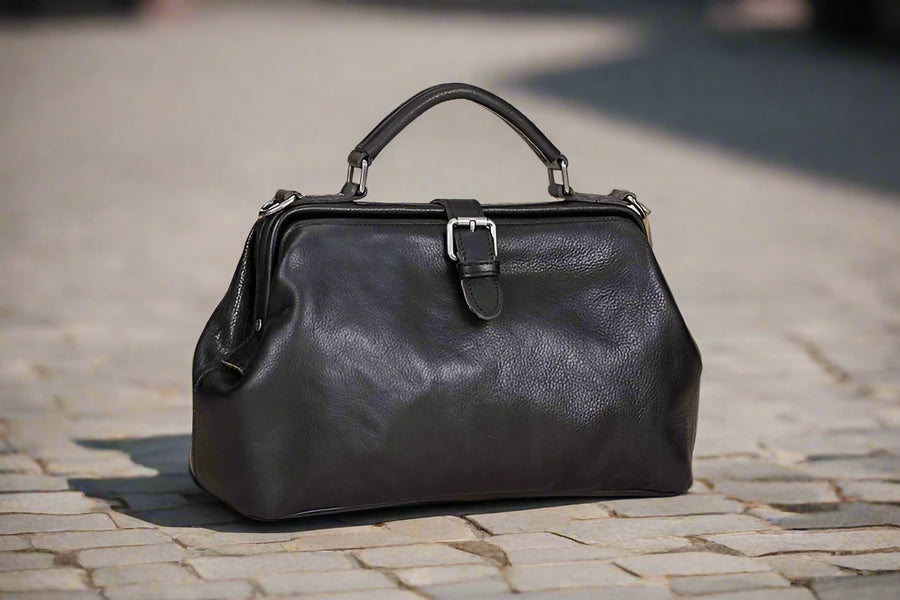 Black leather handbag on a light wooden surface