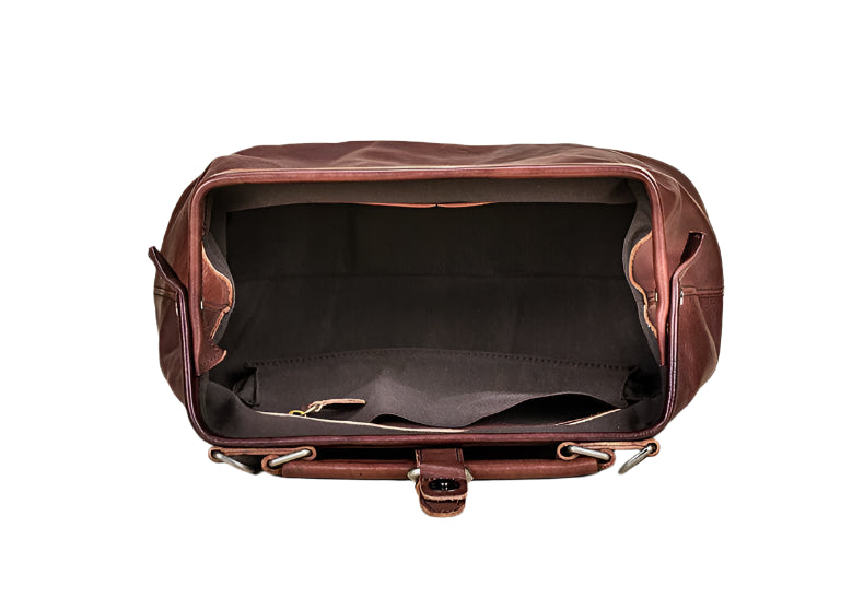 Brown leather duffel bag on a light wooden surface