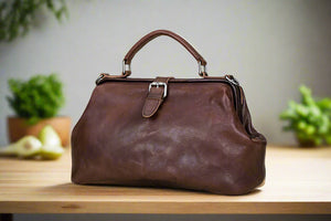 Brown leather handbag on a light wooden surface with a neutral background