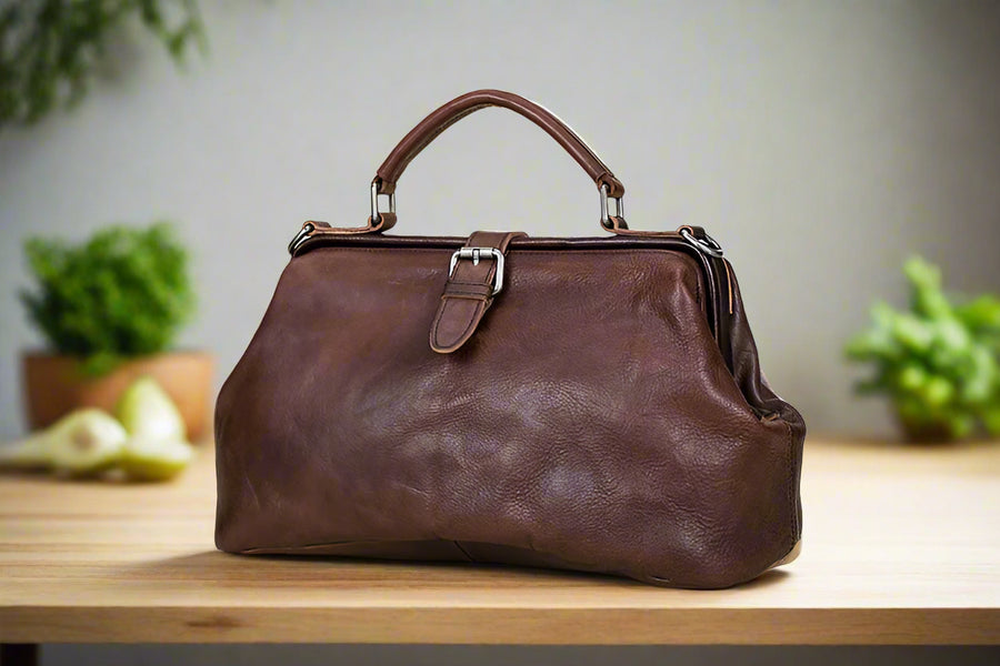 Brown leather handbag on a light wooden surface with a neutral background