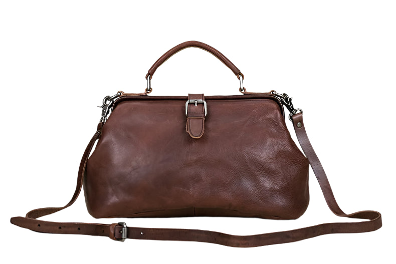 Brown leather handbag with a strap on a light wooden surface