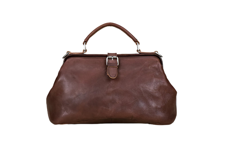 Brown leather handbag on a light wooden surface