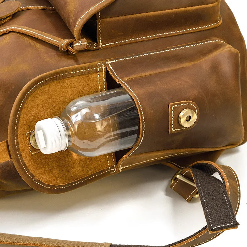 Brown leather bag with a water bottle in an open pocket on a white background